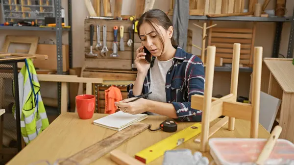 Hispanic Woman Multitasking Carpentry Workshop Talking Phone Taking Notes — Stock Photo, Image