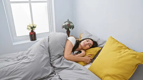 A content woman sleeping peacefully in a cozy bedroom with white walls and yellow pillows