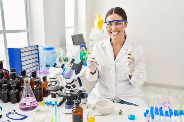 年轻美丽的惊慌失措的女科学家在实验室拿着液体和镊子 — 图库照片