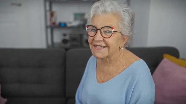 Uśmiechnięta Starsza Kobieta Okularach Siedząca Domu Przedstawiająca Komfort Pozytywność — Zdjęcie stockowe