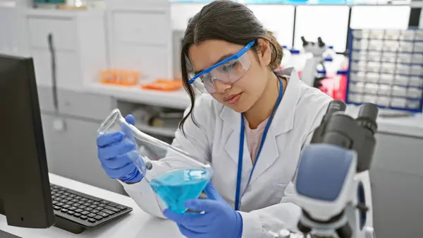 Young Hispanic Woman Scientist Analyzing Blue Liquid Flask Modern Laboratory — Stock Photo, Image