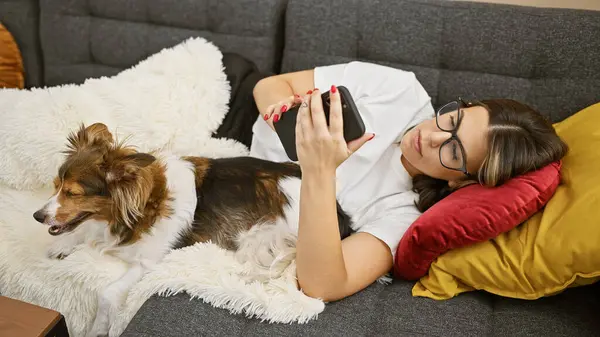 Una Joven Hispana Descansando Con Perro Sofá Interior Usando Teléfono — Foto de Stock
