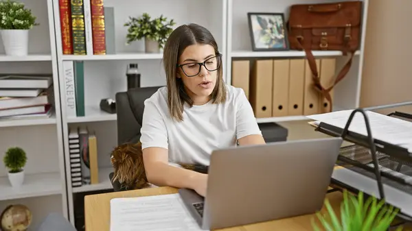 Skupiona Latynoska Kobieta Pracująca Laptopie Biurze Psem Półką Książki — Zdjęcie stockowe