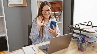 Gözlüklü neşeli bir kadın bilgisayarlı, akıllı telefon dalgalarıyla arıyor..