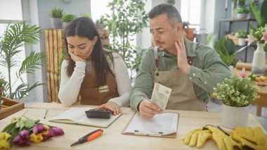 A woman and man in a florist shop ponder over finances with czech currency, amidst vibrant flowers and green plants. clipart