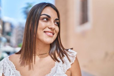 Young beautiful hispanic woman smiling confident looking to the side at street