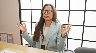 Yakışıklı İspanyol bayan işçi yoga molası veriyor. Ofis evrakları arasında denge ve sükunet arıyor. 