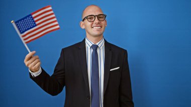 Birleşik Devletler bayrağı taşıyan genç İspanyol iş adamı izole edilmiş mavi arka planda gülümsüyor