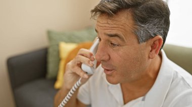 Modern oturma odasında telefon kullanan yakışıklı kıdemli adam..