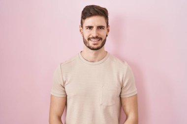 Pembe arka planda sakallı İspanyol bir adam ellerini kavuşturup gülümseyerek gevşemiş ve neşeliydi. Başarı ve iyimserlik 