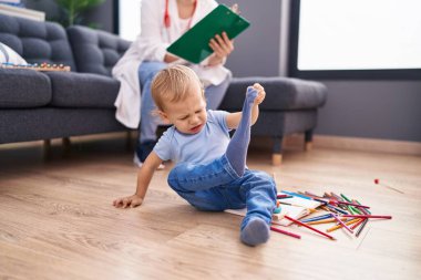 Anne ve oğul doktor evdeki çocuğu muayene eden belgeye yazıyor.