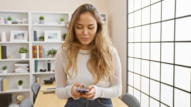 Güzel İspanyol bir kadın, iş adamı, kendini işyerine adamış, akıllı telefonuyla mesajlaşırken ciddi ama rahat titreşimler yayıyor.