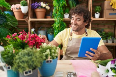 Çiçekçide çiçekçiye dokunan dokunmatik dokunmatik çiçek kullanan İspanyol genç adam.