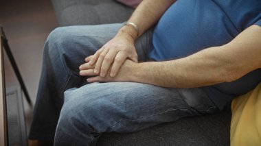 Orta yaşlı bir adam düşünceli bir şekilde bir odanın içinde oturuyor, ellerini kucağında dinlendiriyor, iç huzuru bastıran bir ses tonuyla.