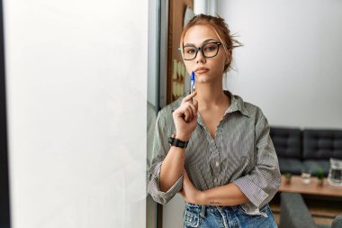 Ofiste ciddi bir ifadeyle duran beyaz kadın iş adamı.