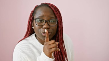 Örgü ören Afrikalı Amerikalı kadın, pembe bir arka plana karşı sessizliğini koruyor..