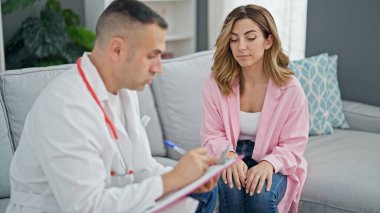 Kadın, erkek, doktor ve hasta klinikte sağlık raporu yazıyor.