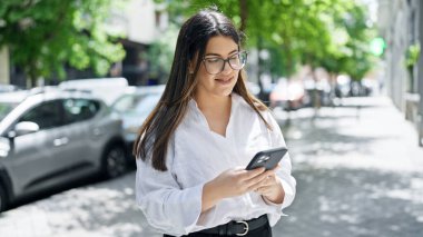 Madrid sokaklarında akıllı telefon kullanarak gülümseyen güzel İspanyol kadın.