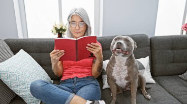 Zeki, gri saçlı orta yaşlı kadın evinde köpeğiyle birlikte rahat bir şekilde edebiyat okuyor, rahat bir yaşam tarzında boş zamanlarının tadını çıkarıyor..