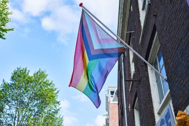 Açık bir gökyüzü karşısında renkli bir gurur bayrağı dalgalanır, lgbtq desteği ve çeşitliliği simgeler..