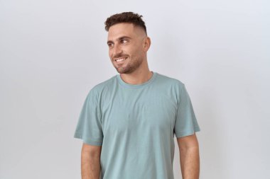 Hispanic man with beard standing over white background smiling looking to the side and staring away thinking. 