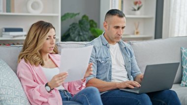 Kadın ve erkek evde dizüstü bilgisayar okuyorlar.