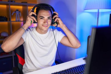 İspanyol asıllı genç adam, gülümsüyor. Oyun masasında kendine güvenen.