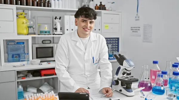 A young male scientist examines a notebook in a laboratory filled with scientific equipment