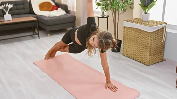 Blonde beauty sweating the stress away, an intimate portrait of a young woman in action, stretching, crunching her abs in a serious home workout inside her comfortable living room