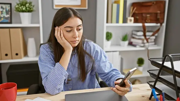 Hispanic Woman Smartphone Modern Office Looking Pensive — Stock Photo, Image