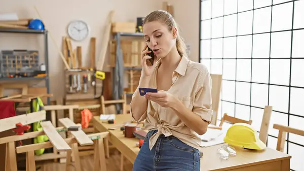Young Woman Multitasking Phone While Holding Credit Card Carpentry Workshop — Stock Photo, Image