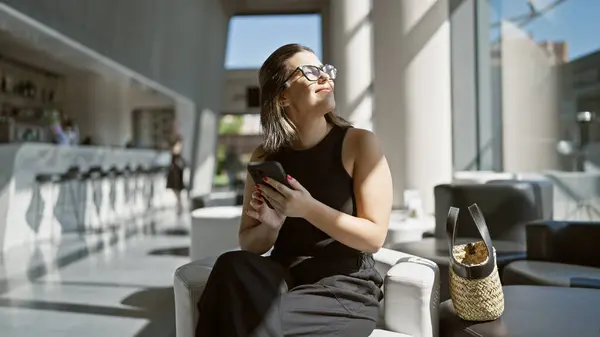 Deliciosa Mujer Hispana Sentada Moderno Hotel Con Gafas Usando Teléfono — Foto de Stock