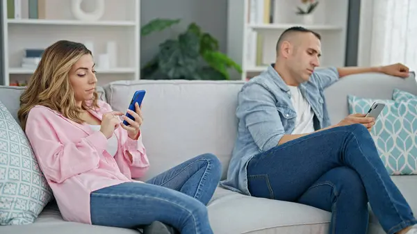 自宅でソファーに座っているスマートフォンを使用して男女カップル — ストック写真