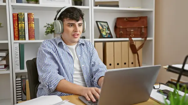 Young Man Headphones Using Laptop Modern Office Setting Surrounded Books — Stock Photo, Image