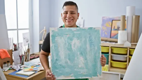 自信的年轻拉丁裔男子快乐地微笑着 自豪地在艺术工作室展示他的才华 激发出他的创造力和激情 — 图库照片