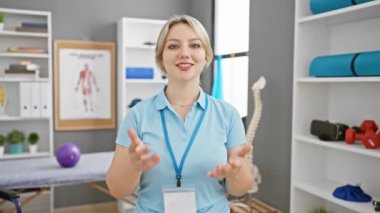 Klinik ortamında hoş geldin diyen beyaz bir kadın, halat takıyor, kendine güveni tamdır..