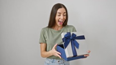 Neşeli genç İspanyol kadın zaferi kutluyor! Güzel dişinin elinde bir doğum günü hediyesi var. İçtenlikle gülümsüyor ve izole edilmiş beyaz bir arka planda zafer için tezahürat yapıyor..