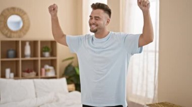 Gülümseyen adam yatak odasında geriniyor, sağlığını ve evdeki günlük hayatını ifade ediyor..
