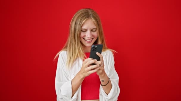 スマートフォンで赤い背景に笑顔の若い女性 — ストック動画
