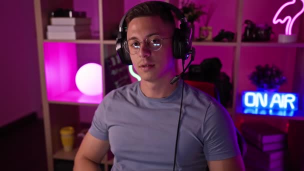 Pria Muda Tersenyum Memakai Headphone Ruang Game Dengan Lampu Neon — Stok Video