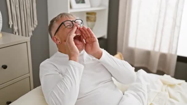 一个白发苍苍的中年男人 在卧室里大声疾呼 双手捂住嘴 穿上运动睡衣 — 图库视频影像