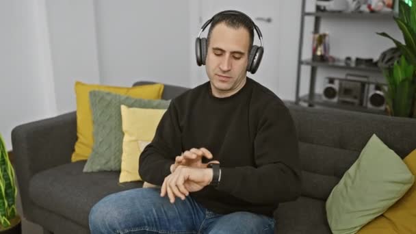 Homem Ouve Música Com Fones Ouvido Sentindo Ritmo Casa Sofá — Vídeo de Stock