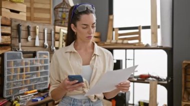 Marangozlukta akıllı telefon okuma belgesi kullanan genç, güzel İspanyol marangoz kadın.