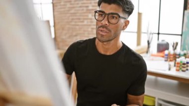 Parlak bir sanat stüdyosundaki tuvale sakallı, odaklanmış bir İspanyol.