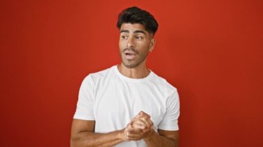 Beyaz gömlekli yakışıklı genç adam ellerini kırmızı duvara dayamış ifade ediyor.