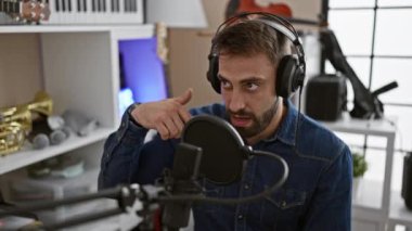 Genç, yakışıklı İspanyol müzisyen, müzik stüdyosunda kulaklık takarak, tutkulu performansına konsantre olarak şarkı söylemeye başlar.