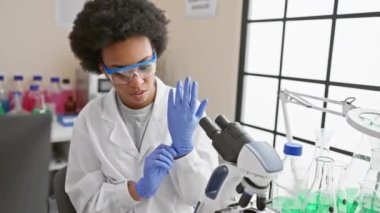Laboratuvarda odaklanmış bir kadın bilim adamı laboratuvar önlüğü giyiyor ve araştırma yaparken koruyucu gözlük takıyor..
