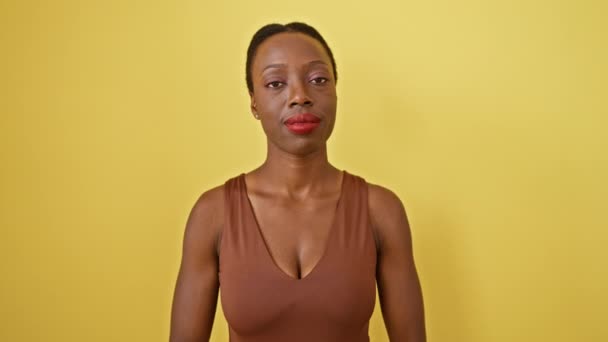 微笑着的非洲裔美国女人 感激地闭上眼睛 双手放在胸前 孤零零地站在黄色的背景上 健康与幸福的肖像 — 图库视频影像