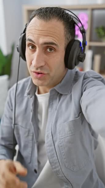 Ein Fröhlicher Mann Mit Kopfhörern Gestikuliert Während Einem Modernen Studio — Stockvideo