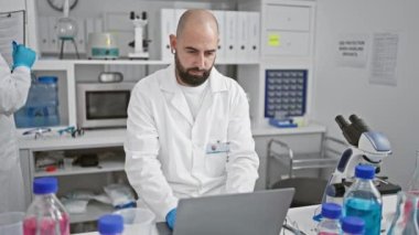 Laboratuvardaki iki ciddi bilim adamı, yüksek teknolojili dizüstü bilgisayar ve pano ellerinde, küçük şeyleri parlak mikroskop altında terletiyorlar, hastane laboratuarında oyun değiştiren raporlar yazıyorlar.